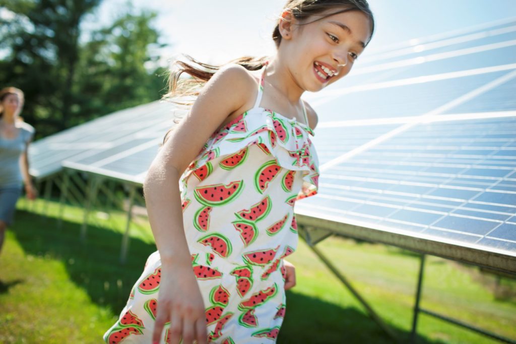 A child and mother beside solar panels in Riverside Mobile Home Park.