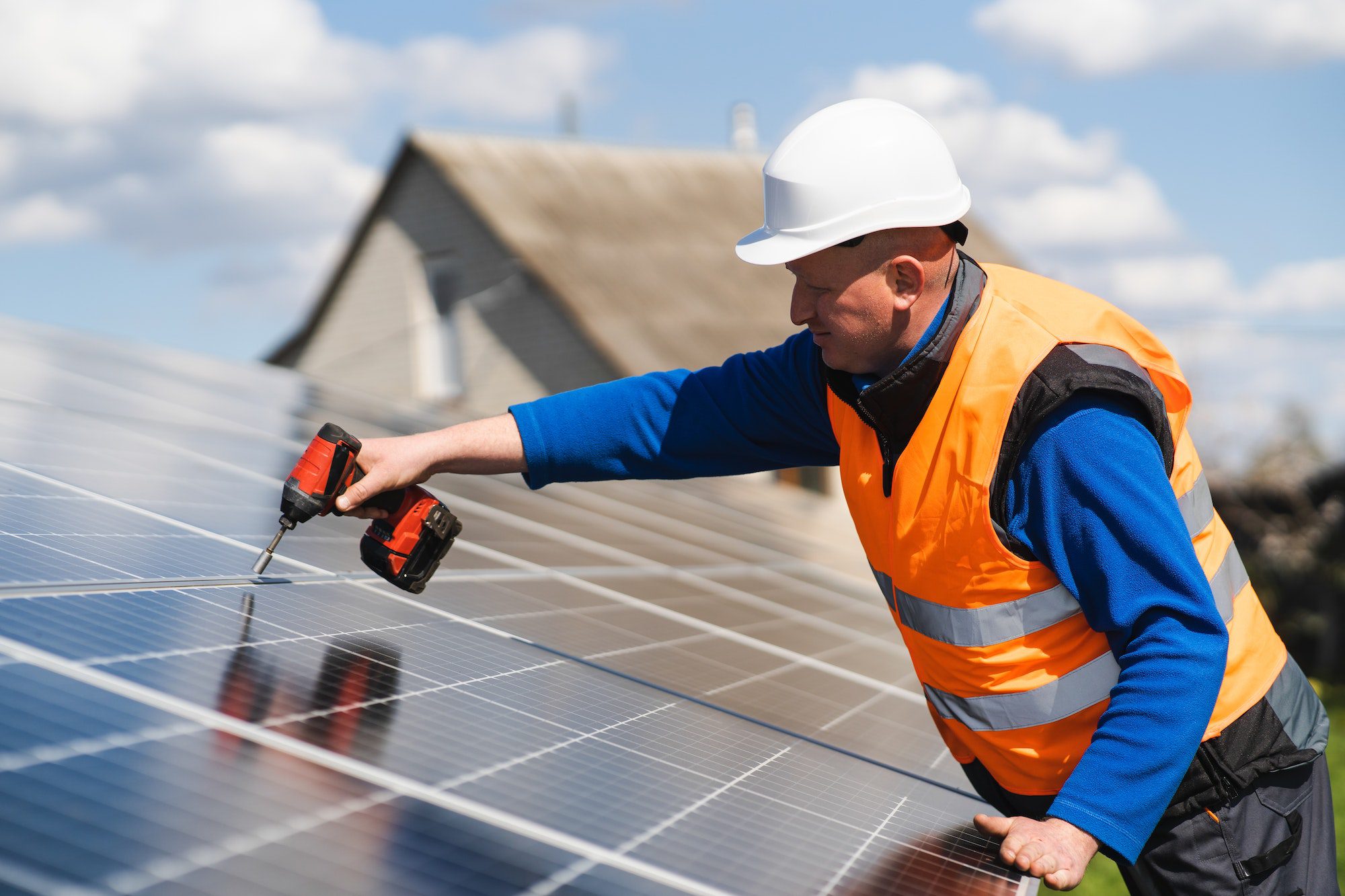 Man with drill screwdriver installs panels at a solar power plant